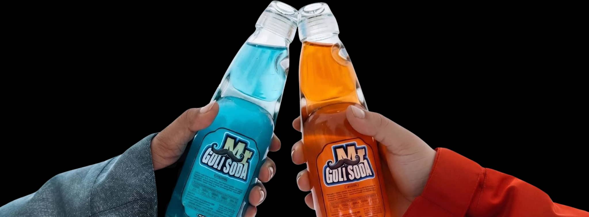 Blue and orange Mr. Goli Soda bottles raised together, with their familiar marble-sealed necks