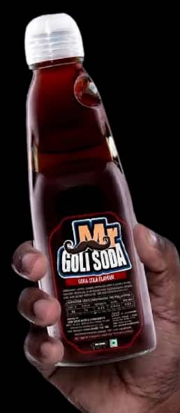 A hand holding a bottle of Jeera Mr. Goli Soda